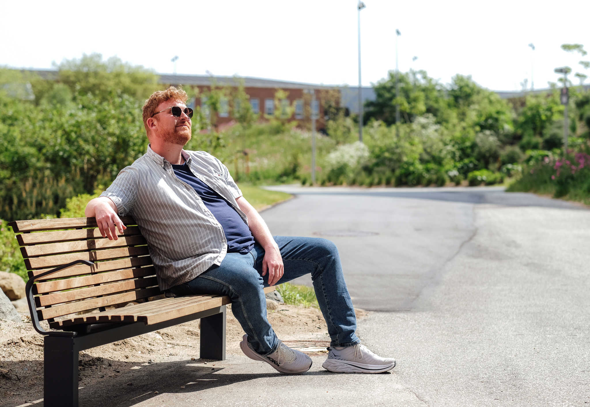Mand, med solbriller på, sidder på bænk