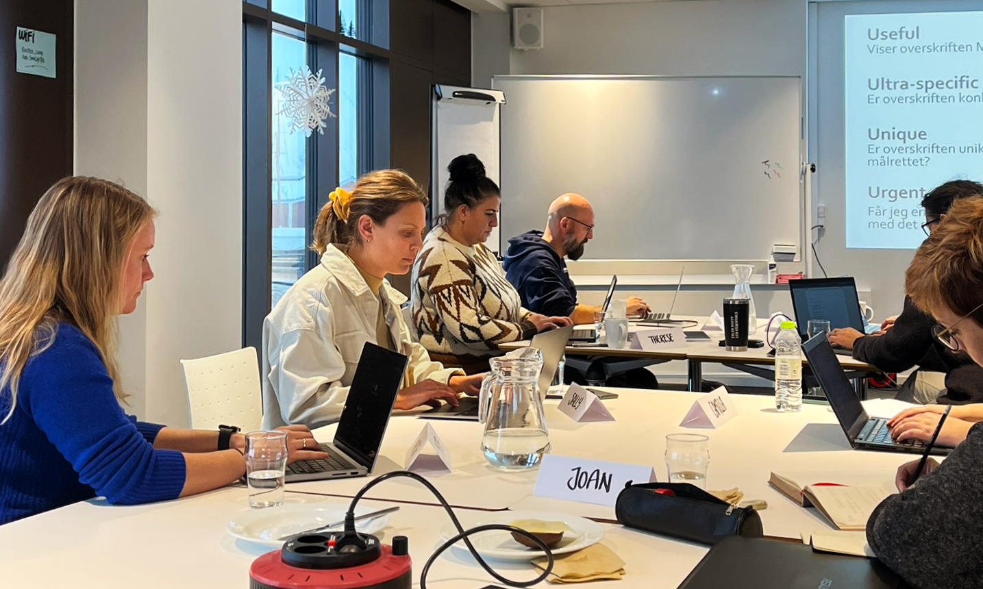 Personer der sidder ved borde og arbejder