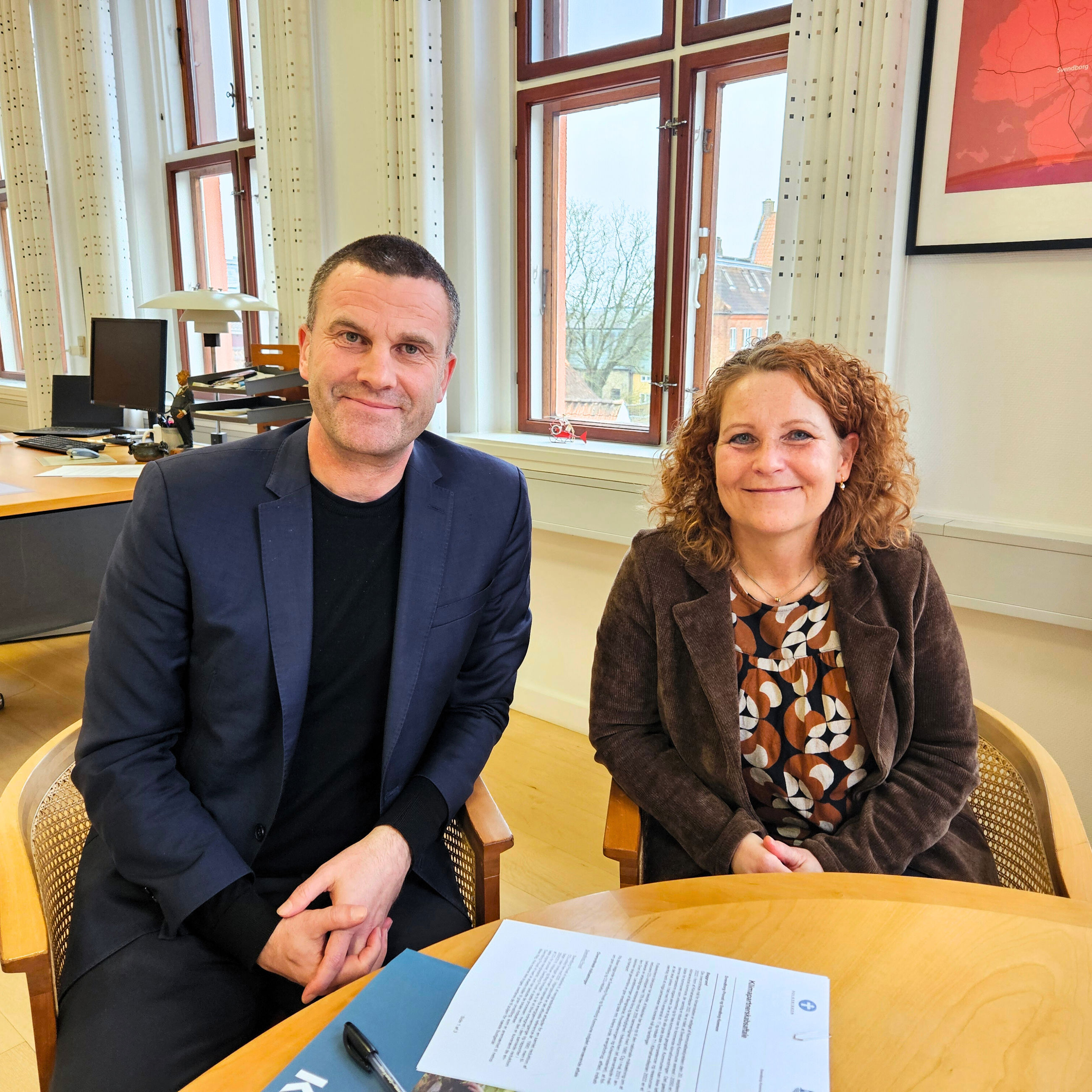 Borgmester Bo Hansen og Provst Bente Holdgaard har netop underskrevet en klimapartnerskabsaftale. De smiler til kameraet.