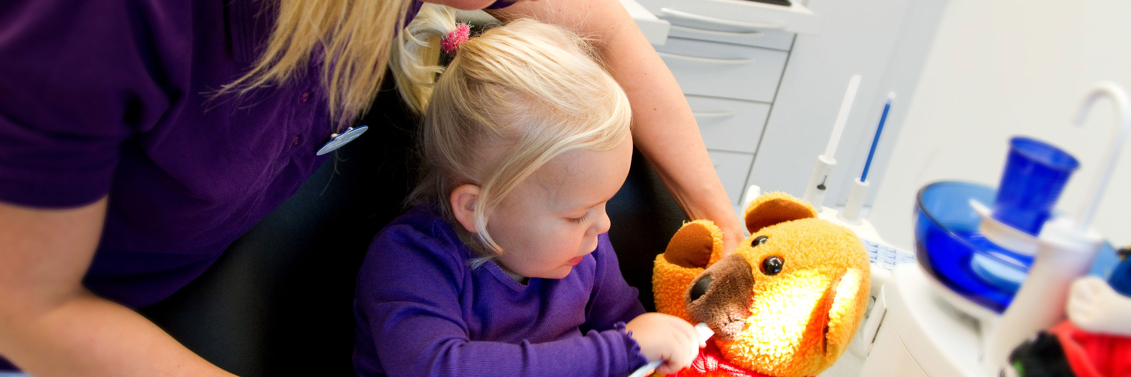 Barn ved tandlægen, børster tænder på bamse.