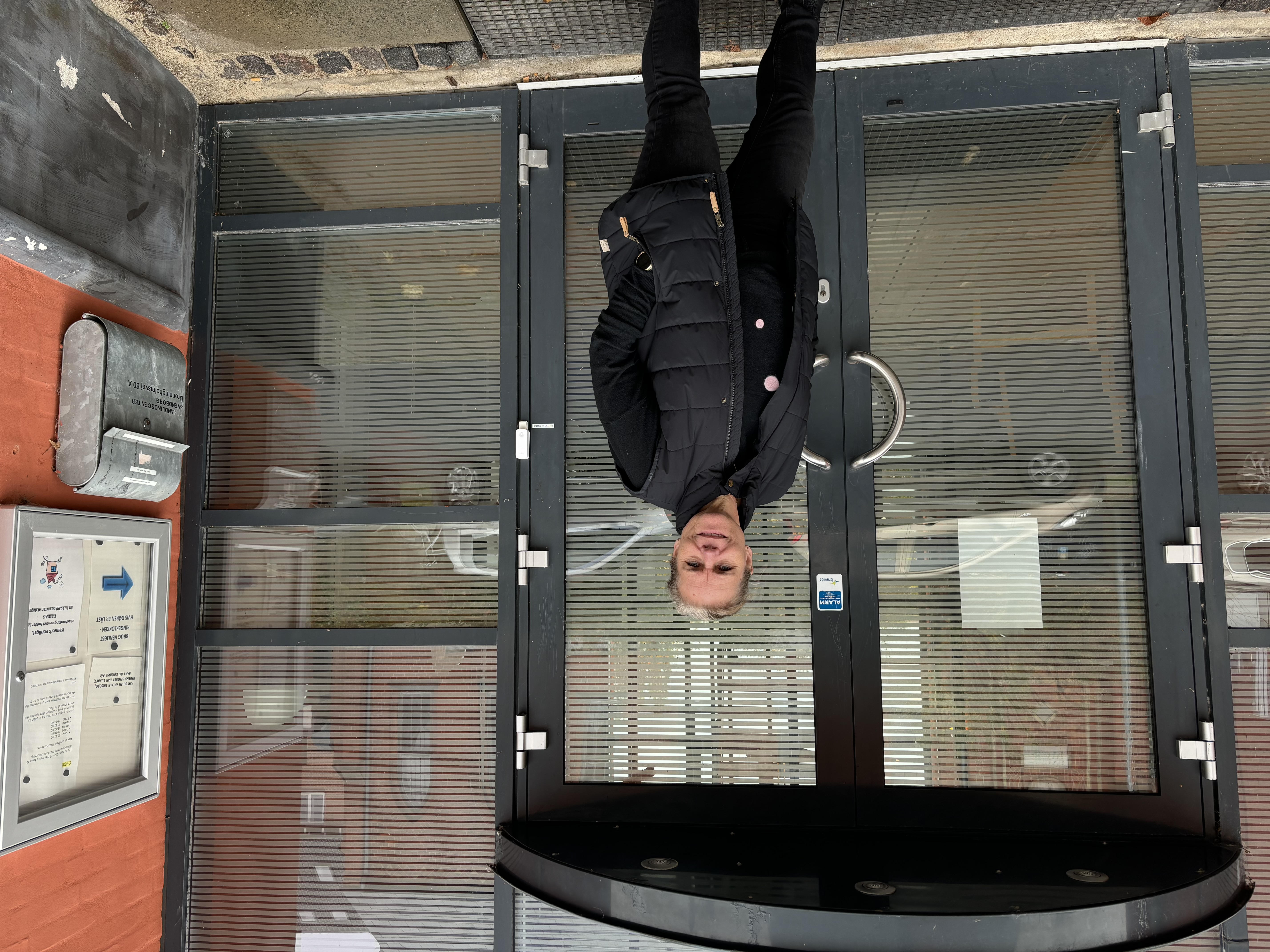 Kvinde i mørt tøj står foran en indgangsdør