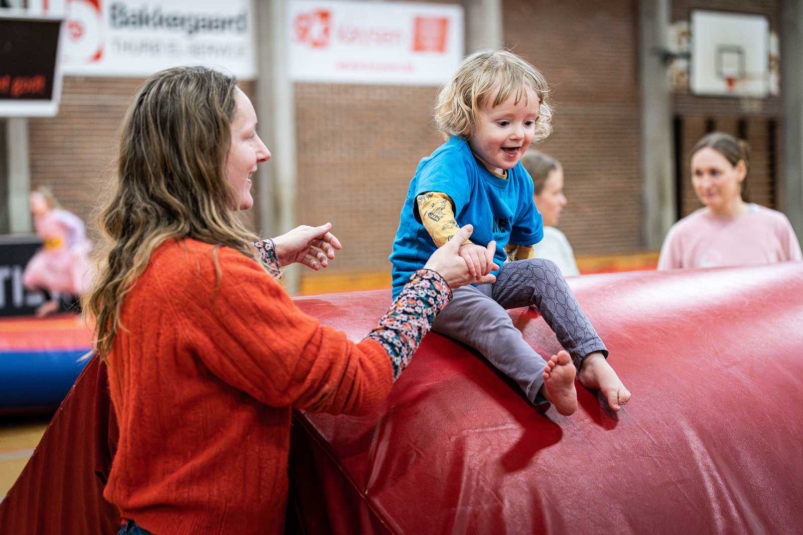 Gymnastik i SG-Huset - en voksen hjælper sit barn i spring fra høj madras