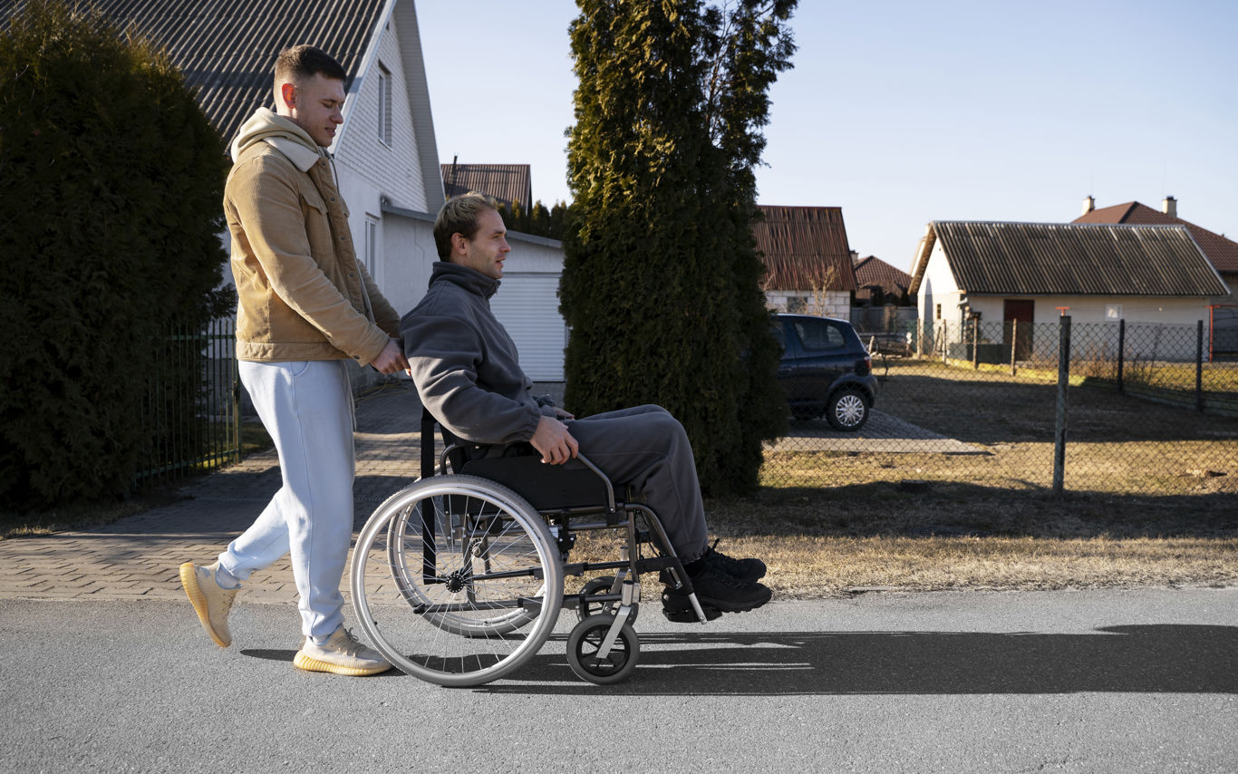 Mand i kørestol med ledsager