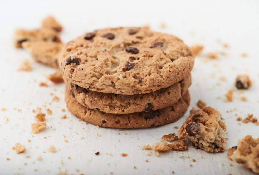 Tre småkager stablet ovenpå hinanden. Der ligger krummer rundt om dem.